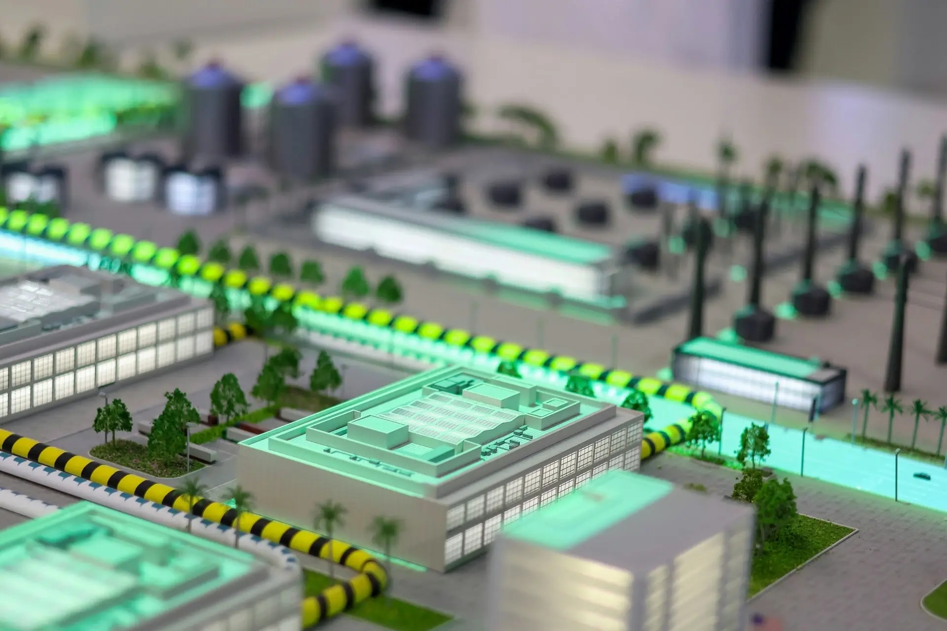 Maquete iluminada de um distrito urbano inteligente, com edifícios modernos e infraestruturas sustentáveis.