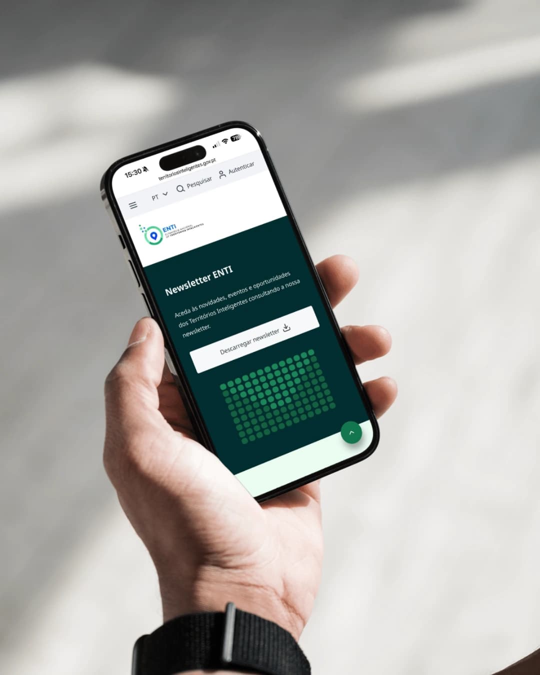 Pessoa segura um smartphone com o Portal dos Territórios Inteligentes aberto, onde é possível descarregar a newsletter na página inicial.