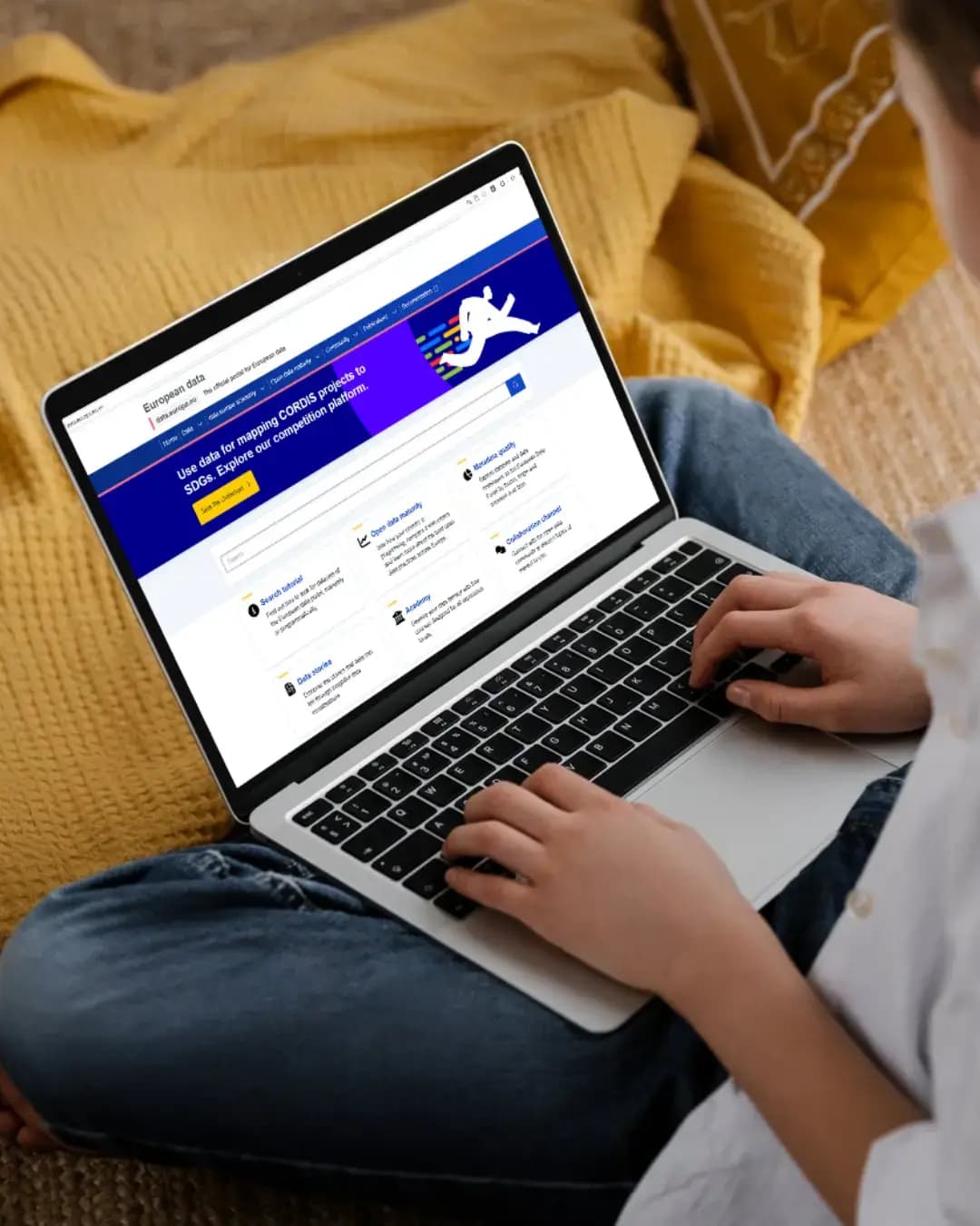 Pessoa sentada num sofá a utilizar um computador portátil com o portal europeu de dados aberto no ecrã.